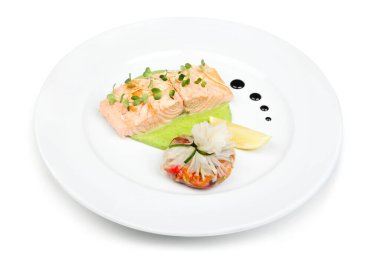 Beyaz bir tabakta sebze püresi, karides ve dekoratif sos ile servis edilen zarif somon yemeği.