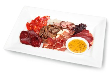 Salam ve prosciutto da dahil olmak üzere dilimlenmiş et çeşitleri, hardal soslu beyaz dikdörtgen bir tabakta servis edilir.