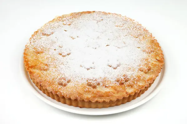 stock image Close-up of a freshly baked pie dusted with powdered sugar, presented on a white background, showcasing its golden crust.