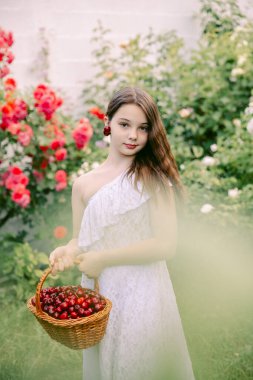 Kız gülüyor ve kulağına küpe gibi kiraz tutuyor.