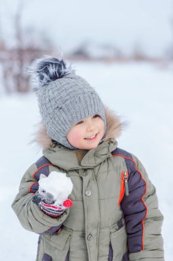 Küçük çocuk kartopu oynuyor, gülümsüyor ve mutlu.