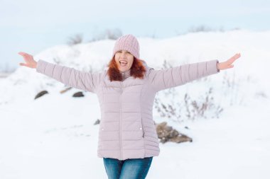 Kışın giyinmiş kadın kollarını açmış ve duygusal olarak mutlu.