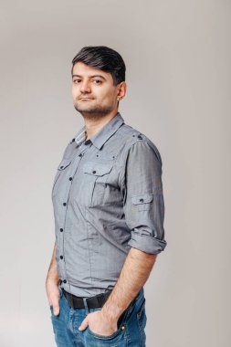 Ellerini pantolonunun cebinde tutan ve doğrudan objektife bakan açık arka planda genç bir adamın portresi.
