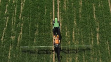 Yay tarlasında traktörün hava görüntüsü. Yeşil traktörün üzerinden uçan İHA 'dan ateş ederek alana kimyasallar püskürtüyor. Tarım konsepti. Kırsal alan.