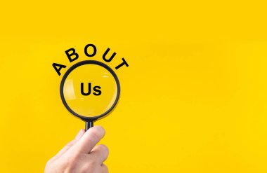 Phrase about us with magnifying glass on yellow background