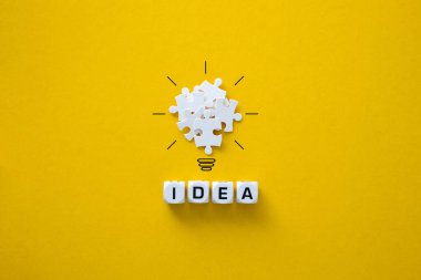 Light bulb from puzzles on yellow background. Inspiration and creative idea concept.