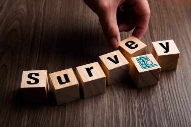 El, tahta küp bloğu koydu ve kelime SURVEY oluşturdu. Sınav ve geri bildirim konsepti. Anket arkaplanı
