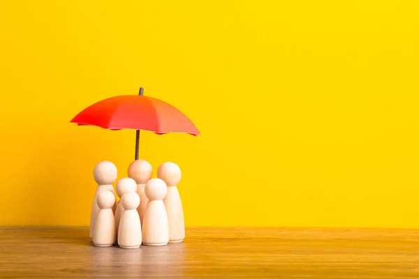 Umbrella and wooden doll figures. Insurance coverage concept.