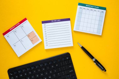 Yönetici hafta düzenleme takvim, aylık planlayıcı kullanarak ve sarı masa üzerinde liste yapmak
