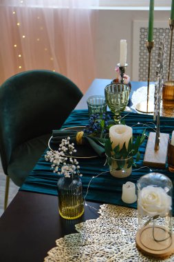 Table set for wedding or another catered event dinner. The luxury served table indoors in green colors. Dark wooden table, beautiful evening restaurant with luxury decor