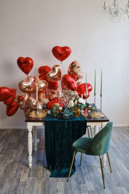 Festive table setting in dining room decorated for Valentine's Day. Decorated table for two with large heart shaped balloons