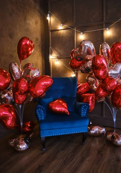 Loft style interior with blue armchair decorated with lots of heart shaped balloons for Valentine\'s Day or other romantic or festive event. Be special Valentine concept