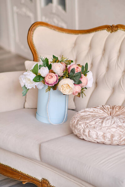 Large bouquet of decorative flowers in a pink hat box in Luxurious interior beautiful classical white interior with white sofa. Spring, flowers, gifts, decorations