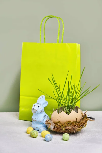 Green shopping bag, green grass in Easter egg, with copy space. Online shopping for the holidays. Symbols, traditions concept.