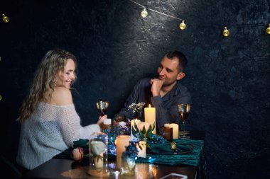 Güzel bir çift karanlık bir restoranda mum ışığında bir masada oturuyor. Erkek, eşi ön planda otururken, göz açıp kapayıncaya kadar ortağına bakar..