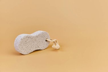 Bej arka planda volkanik sünger taşı, tek bir nesne. Banyo aksesuarları, vücut, cilt ve ayak bakımı, kopyalama alanı
