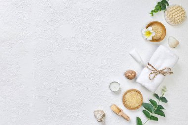 Spa tedavisi konsepti. Doğal kaplıca ürünleri, deniz tuzu, deniz taşı, masaj fırçası, yukarıdan beyaz desenli arka plan havlusu. Metin, düz alan, üst görünüm için bir arkaplan