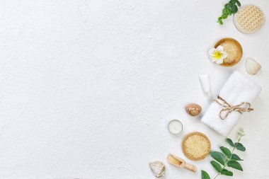 Kozmetik, masaj ve banyo aksesuarları beyaz doku arka planında, beyaz çiçek, yeşil yapraklar. Kozmetik modeli. Düz görünüm kopyalama alanı yatıyordu. Marka ürünleri, güzellik geçmişi