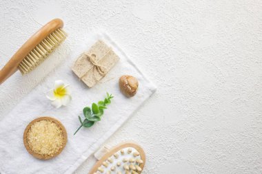 Kozmetik, masaj ve banyo aksesuarları beyaz doku arka planında, beyaz çiçek, yeşil yapraklar. Kozmetik modeli. Düz görünüm kopyalama alanı yatıyordu. Marka ürünleri, güzellik geçmişi