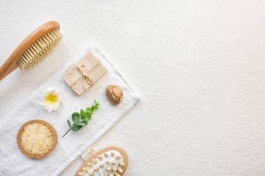 Kozmetik, masaj ve banyo aksesuarları beyaz doku arka planında, beyaz çiçek, yeşil yapraklar. Kozmetik modeli. Düz görünüm kopyalama alanı yatıyordu. Marka ürünleri, güzellik geçmişi