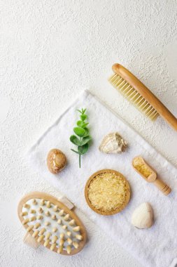 Kozmetik, masaj ve banyo aksesuarları beyaz doku arka planında, beyaz çiçek, yeşil yapraklar. Kozmetik modeli. Düz görünüm kopyalama alanı yatıyordu. Marka ürünleri, güzellik geçmişi