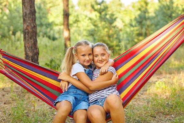 stock image Kids relax in colorful rainbow hammock. Hot day garden outdoor fun. Afternoon nap during summer vacation. Children relaxing.