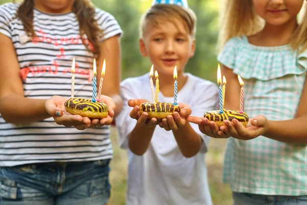 孩子们拿着生日蛋糕 点着蜡烛 孩子们的派对装饰和食物 男孩和女孩在花园里用吊床庆祝生日 吃糖的孩子 — 图库照片