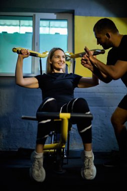 Koyu renk bir spor salonunda spor salonunda spor yaparken spor aletini kullanmasına yardımcı olan özel koç.