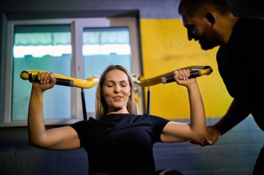 Koyu renk bir spor salonunda spor salonunda spor yaparken spor aletini kullanmasına yardımcı olan özel koç.