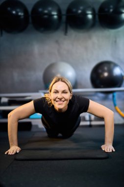 Genç çekici sportif kadın aktif giysi giyiyor GYM 'de egzersiz yapıyor, kapalı alanda çalışıyor, sağlıklı aktif yaşam tarzı konsepti.