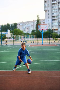 Oyun sahasında basketbol oynayan neşeli, genç bir çocuk. Çocuk, şehir binalarının arka planına karşı Red Court 'ta sahne alıyor. Aktif yaşam tarzı, eğitim, profesyonel spor