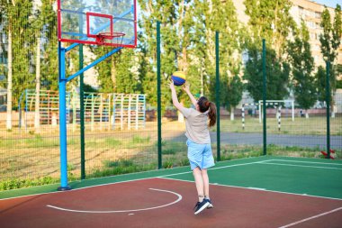 Oyun sahasında basketbol oynayan neşeli, genç bir kız. Şehir binalarının arka planında Red Court maçında şut atan bir kız. Aktif yaşam tarzı, eğitim