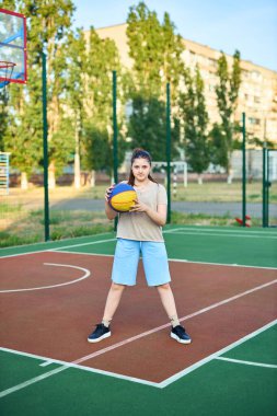 Neşeli beyaz bir kızın hayat tarzı portresi. 10 yaşında, sıcak yaz gününde basketbol topu tutuyor. Aktif yaşam tarzı, eğitim, profesyonel spor