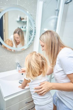 Annem çocuk ellerine banyoda sabunla yıkamayı öğretiyor.