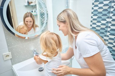 Annem çocuk ellerine banyoda sabunla yıkamayı öğretiyor.