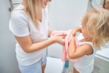 Duş, hijyen ve temiz çocuk şefkatli, sevgi dolu ve nazik bir anneyle bağ kuruyor. Bekar kadın ebeveyn evdeki banyoda sıcak bir banyo yaptıktan sonra çocuğunu yumuşak, kuru ve pembe bir havluyla kurutuyor.