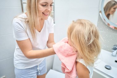 Duş, hijyen ve temiz çocuk şefkatli, sevgi dolu ve nazik bir anneyle bağ kuruyor. Bekar kadın ebeveyn evdeki banyoda sıcak bir banyo yaptıktan sonra çocuğunu yumuşak, kuru ve pembe bir havluyla kurutuyor.