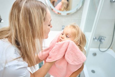 Duş, hijyen ve temiz çocuk şefkatli, sevgi dolu ve nazik bir anneyle bağ kuruyor. Bekar kadın ebeveyn evdeki banyoda sıcak bir banyo yaptıktan sonra çocuğunu yumuşak, kuru ve pembe bir havluyla kurutuyor.