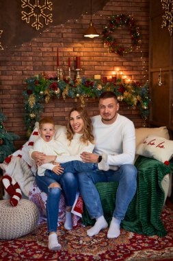 Mutlu aile Noel ağacının yanında sımsıkı sarılıyor ve güzel bir evde Noel arifesinde neşeyle gülümsüyor.