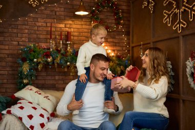 Noel ağacının yanında mutlu aile hediyeleri ve güzel bir evde Noel arifesinde neşeli bir gülümseme.