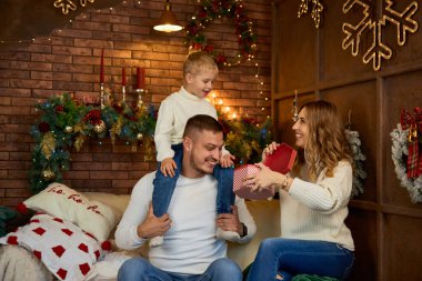 Noel ağacının yanında mutlu aile hediyeleri ve güzel bir evde Noel arifesinde neşeli bir gülümseme.