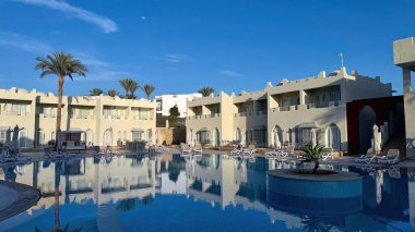 Mısır 'ın lüks tatil köyündeki güzel boş yüzme havuzu alanı. Güneşli bir günde geniş açılı çerçeve.