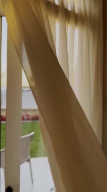 Rüzgâr perdeyi indirir ya da Otel Tatil Köyü 'nde sallanır, Mısır' da. Teraslı güneşli bir gün. Sakin sakin bir sabah. Güneş tülün içinden pencereye doğru parlıyor. İç mekan