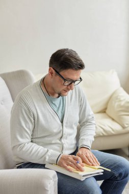 Yakışıklı erkek psikoloğun portresi ve klinikteki terapi sırasında not almak. Sevgili milenyum psikoterapisti ofiste poz veriyor ve gülümsüyor.