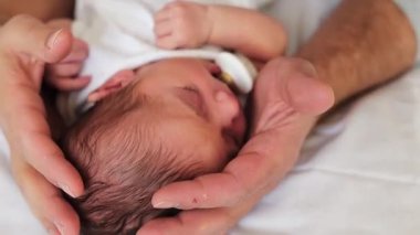 Yeni doğmuş bebek annesinin ellerinde uyuyor.