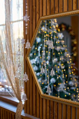 Cam çanların ve kar tanelerinin asılı olduğu zarif Noel atmosferi aynaya yansıyan neşeli bir ağaçla, samimi bir tatil ruhunu çağrıştırıyor.
