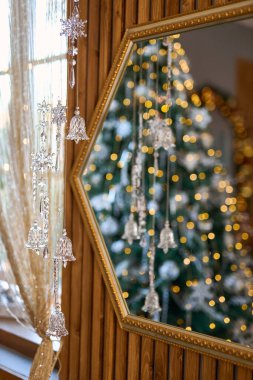 Cam çanların ve kar tanelerinin asılı olduğu zarif Noel atmosferi aynaya yansıyan neşeli bir ağaçla, samimi bir tatil ruhunu çağrıştırıyor.