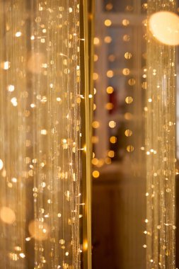 Ilık altın bokeh ışıkları ve narin parıldayan ipliklerle dolu ışıl ışıl bir arka plan, kutlama ve lüks temalar için uygun şenlikli, zarif ve soyut bir aydınlatma efekti yaratıyor.