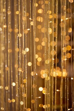 Ilık altın bokeh ışıkları ve narin parıldayan ipliklerle dolu ışıl ışıl bir arka plan, kutlama ve lüks temalar için uygun şenlikli, zarif ve soyut bir aydınlatma efekti yaratıyor.