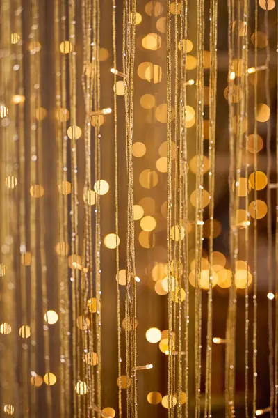 Ilık altın bokeh ışıkları ve narin parıldayan ipliklerle dolu ışıl ışıl bir arka plan, kutlama ve lüks temalar için uygun şenlikli, zarif ve soyut bir aydınlatma efekti yaratıyor.